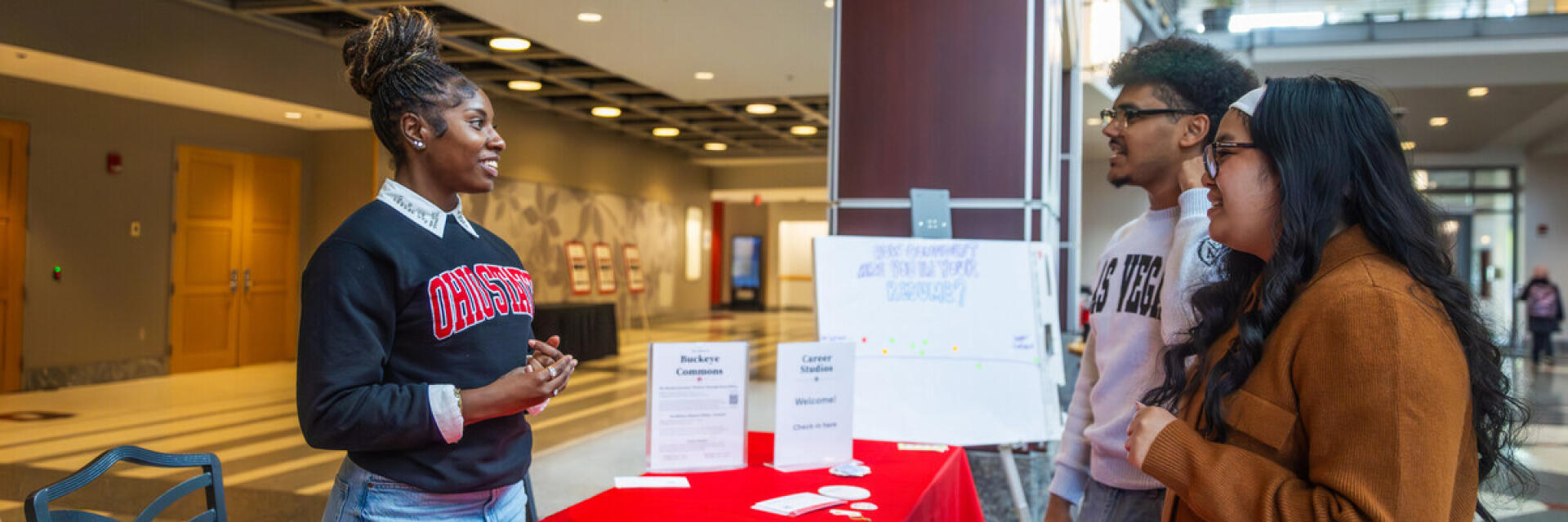 A student standing behind a table and sharing information with other students